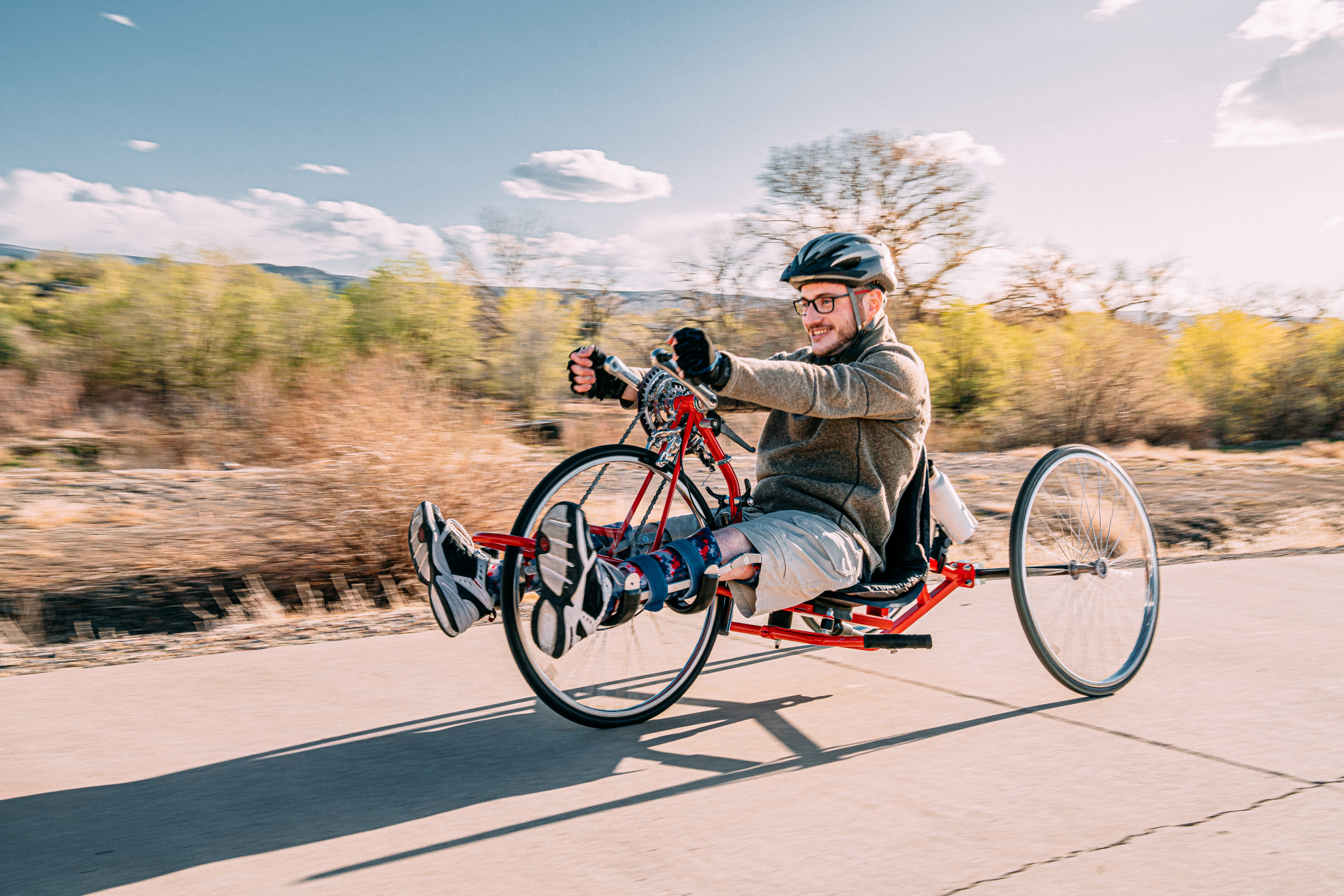 Cyclist using a recumbent bicycle cycling along a track in the countryside to demonstrate access to cycling for everyone