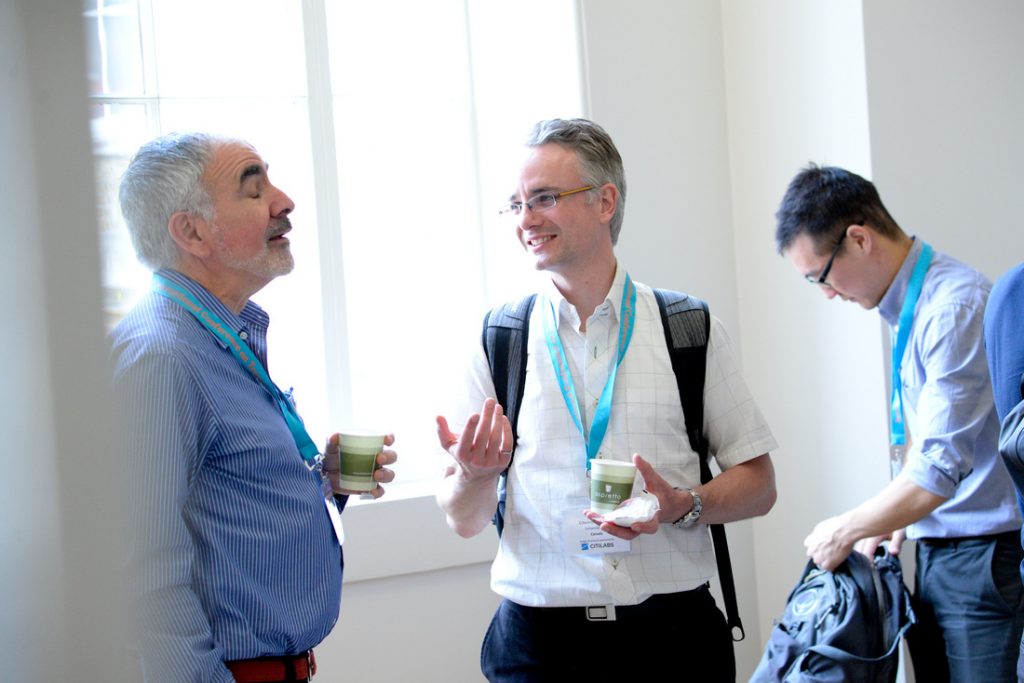 3 men standing at the ICTH conference informally chatting whilst holding drinks