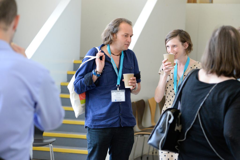 Man and woman at a conference standing holding a hot drinking and talking