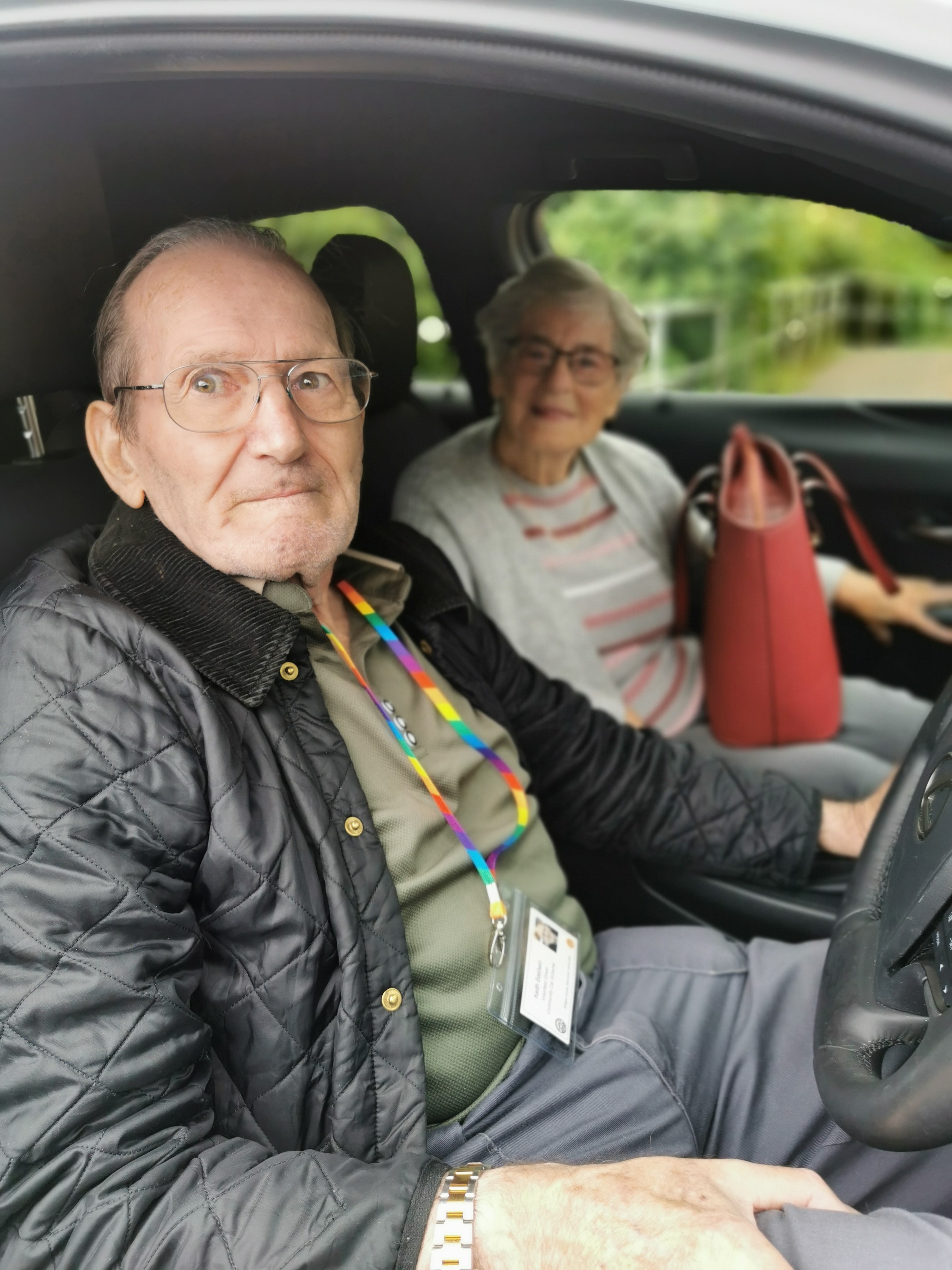 Gallery of three photos one with a man standing between three older ladies infront of a car, one with a lady heloing somone into a new electric minibus and one with two people sat in the front of a car.